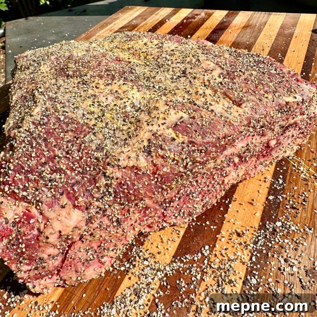Seasoned rack of raw beef ribs on a cutting board.