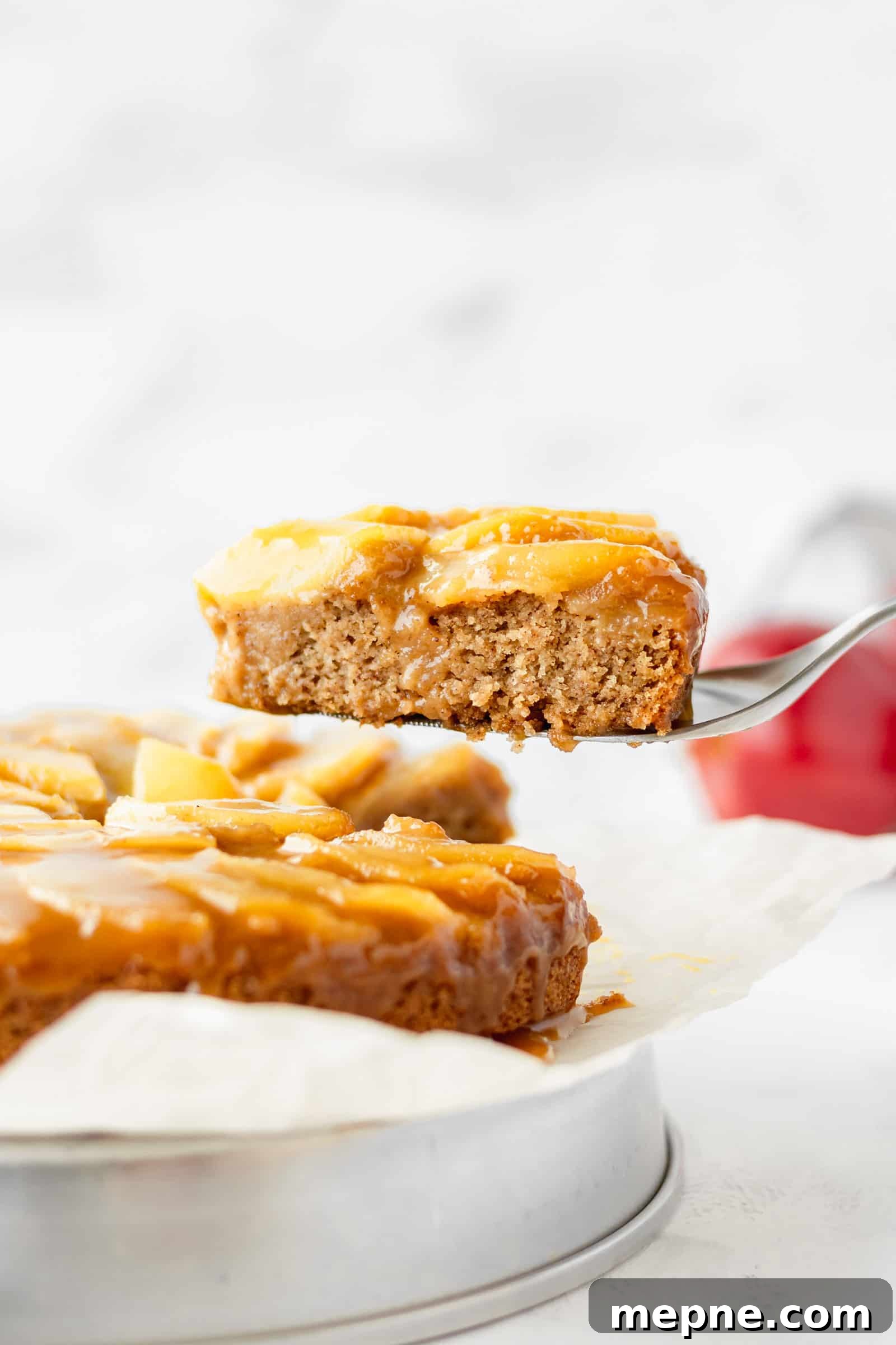 Vegan Apple Cake Recipe with Cinnamon Streusel 2 A slice of vegan apple cake being lifted up.