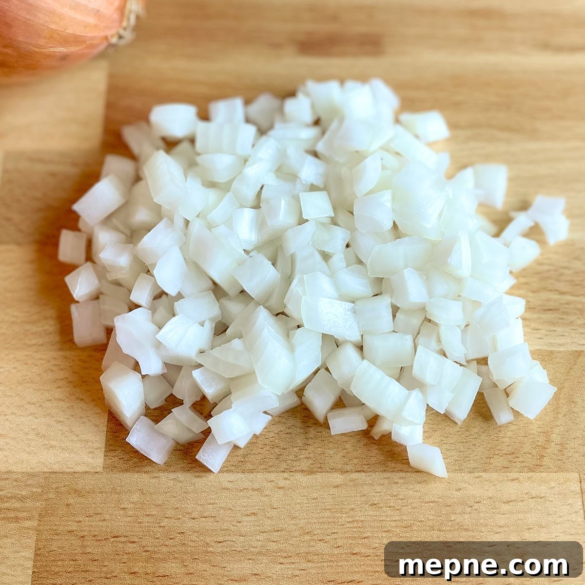 Pineapple Pico de Gallo Recipe: Tropical Salsa 6 Diced yellow onion with a yellow onion in the background on a butcher block cutting board
