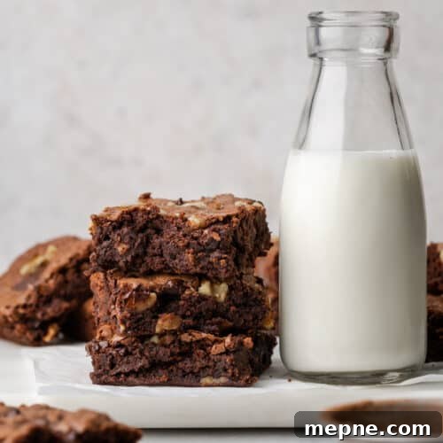 A stack of gluten free brownies next to a jug of milk.