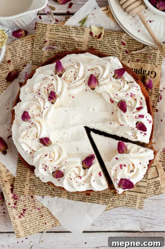 A golden honey rose cake topped with white rose buttercream and bright pink rosebuds.