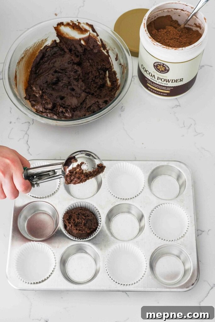 Moist and Fudgy Double Chocolate Muffins Recipe 11 A cookie scoop portions muffin batter into a lined muffin pan.