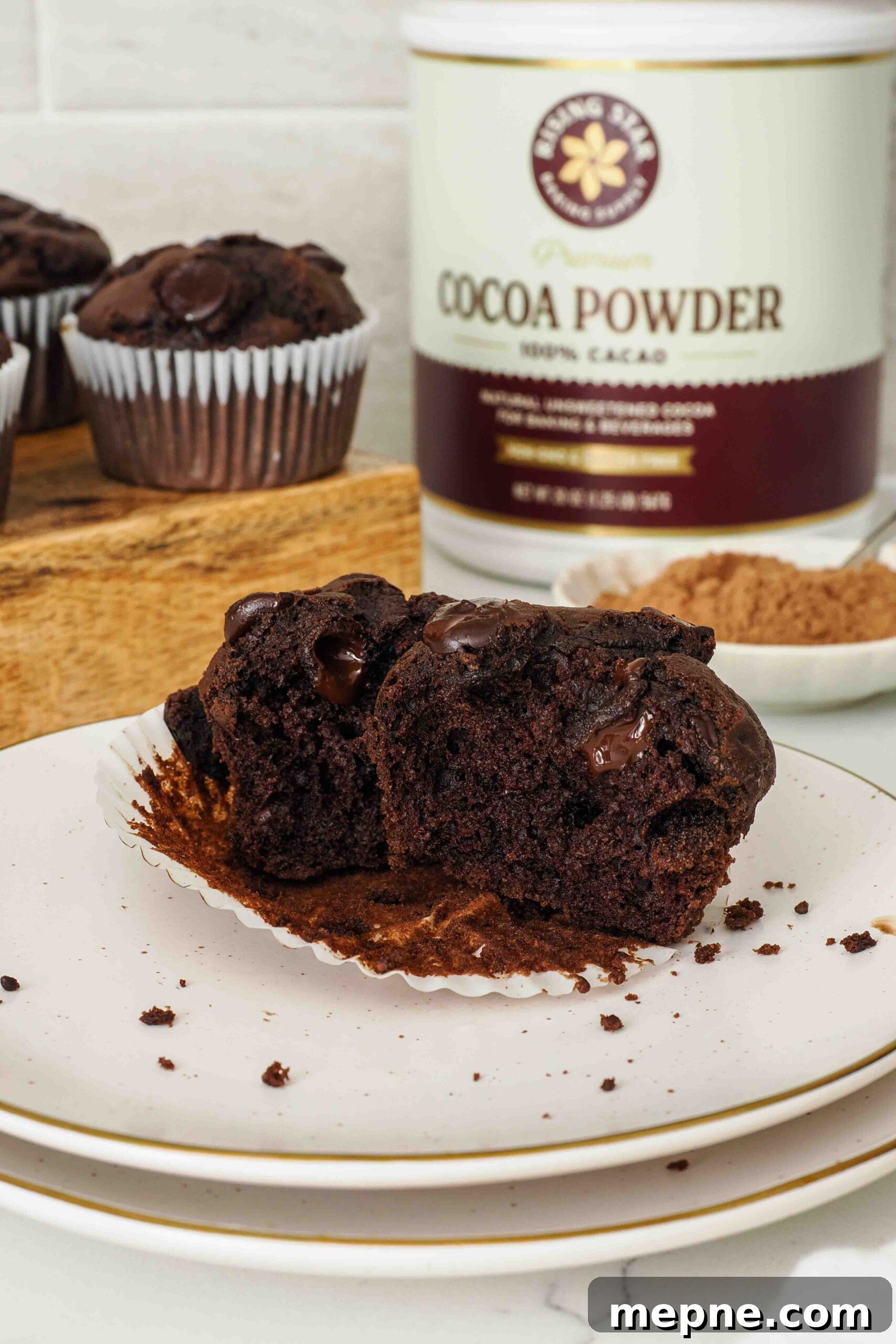 Moist and Fudgy Double Chocolate Muffins Recipe 14 A double chocolate muffin is split in half on a counter.
