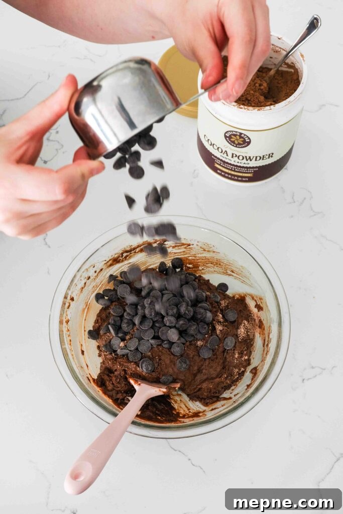 Moist and Fudgy Double Chocolate Muffins Recipe 8 Chocolate chips are dumped into a bowl of chocolate muffin batter.