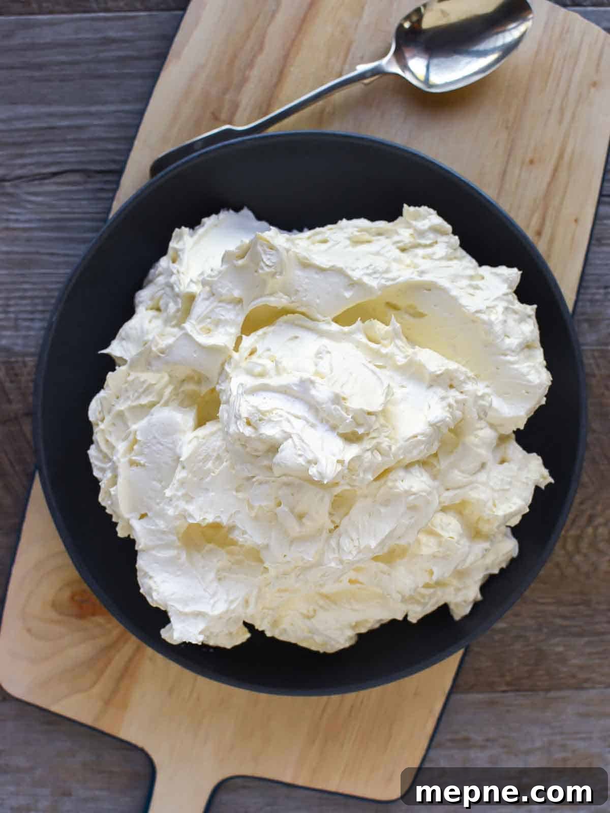How to Make Italian Meringue Buttercream 3 Thick creamy buttercream in black bowl viewed from above.