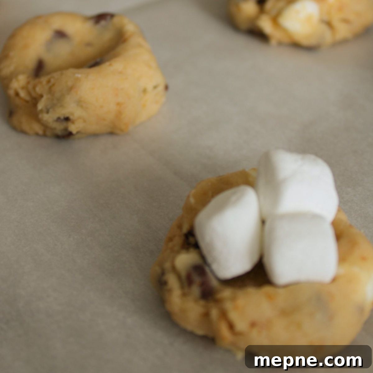 Cookie dough balls with marshmallows placed on top.