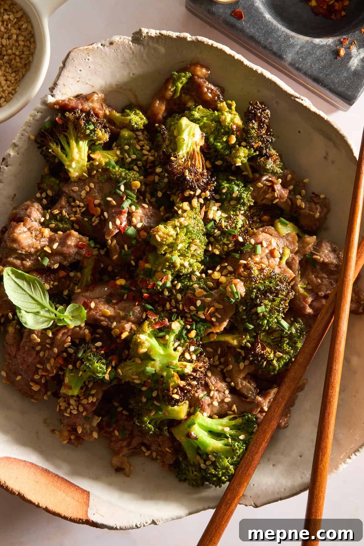 Crispy Air Fryer Beef and Broccoli Recipe 2 A bowl of air fryer beef and broccoli with chopsticks balanced on the side.