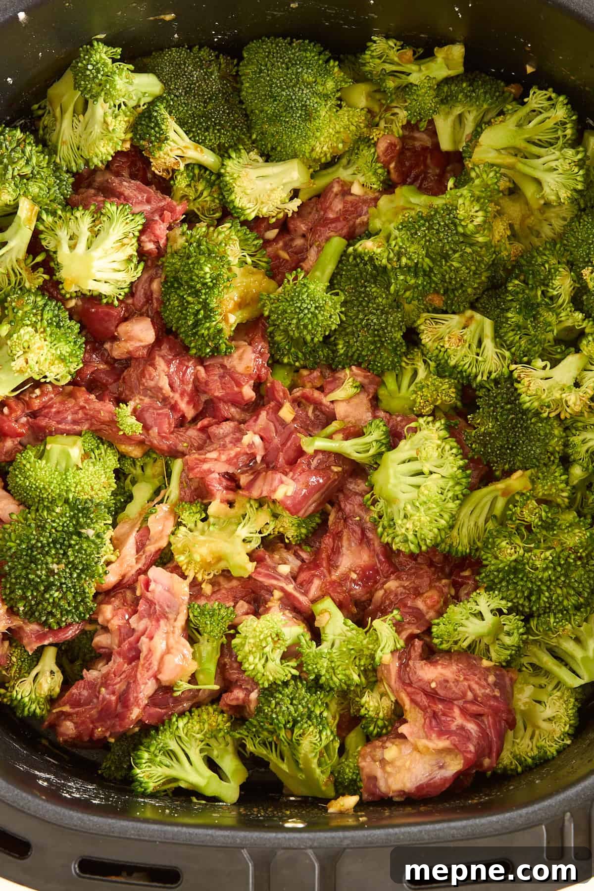 Crispy Air Fryer Beef and Broccoli Recipe 4 Raw air fryer beef and broccoli in an air fryer basket.