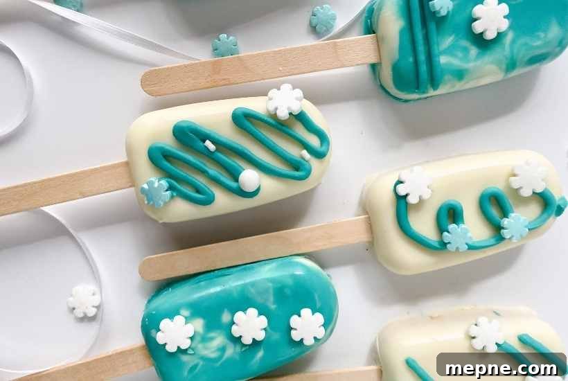 Close up of Frozen themed cakesicles with blue and white icing and snowflake sprinkles.