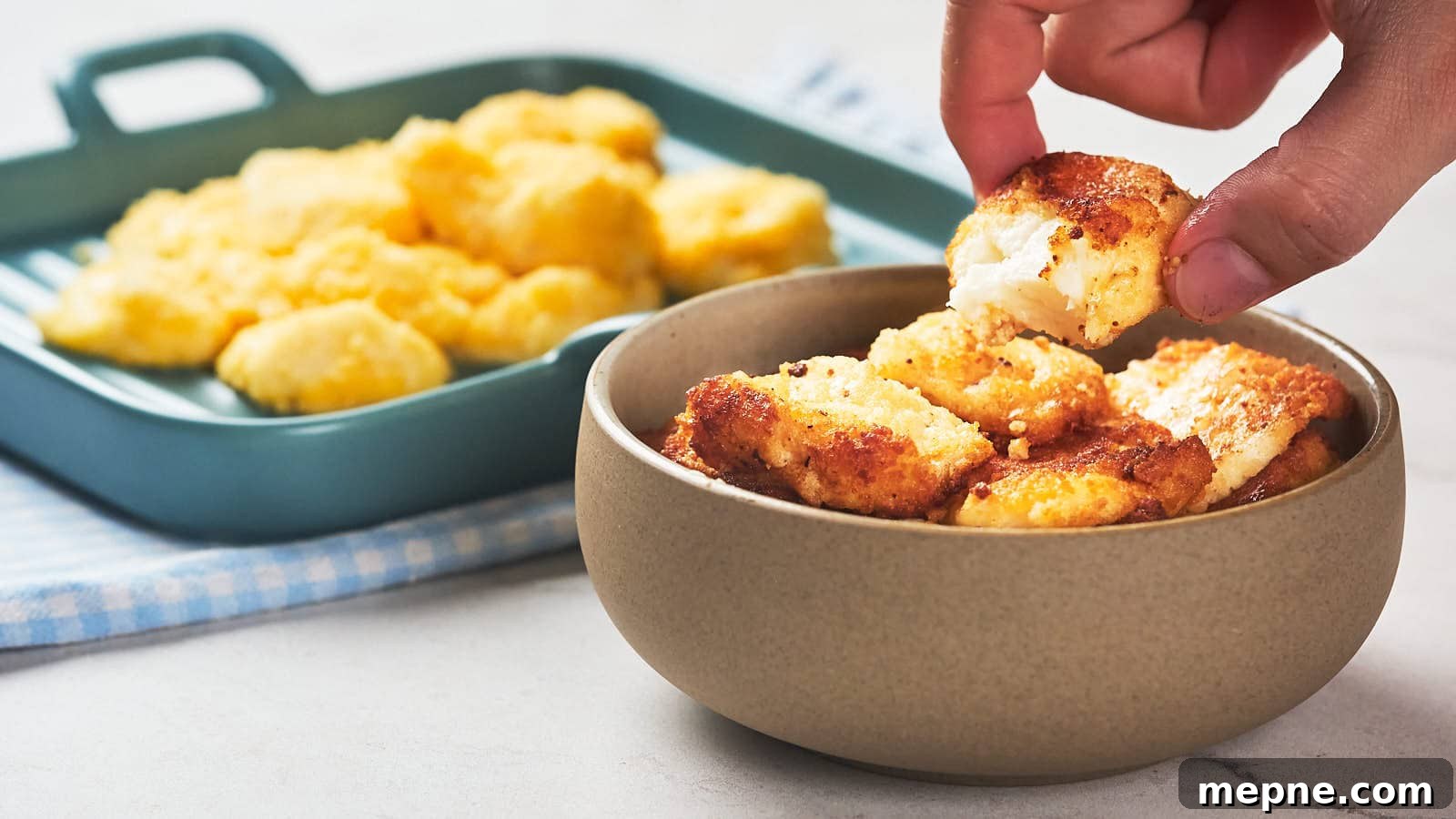 13 Low-Carb Holiday Appetizers to Impress Guests 4 A hand picks up a piece of fried cheese curd from a bowl.