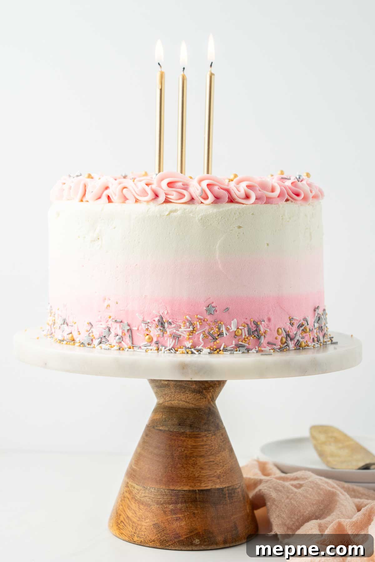 Vegan Vanilla Cake with Fluffy Frosting 2 Vegan birthday cake with gold candles on a marble and wood cake stand.