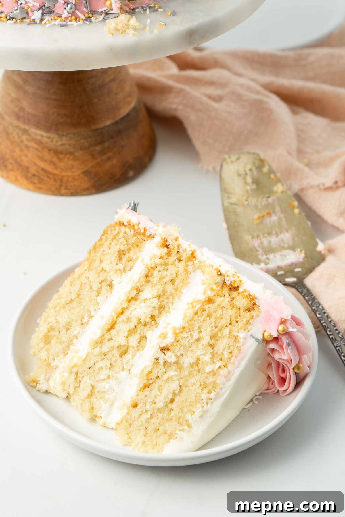 Vegan Vanilla Cake with Fluffy Frosting 5 Close up of a large slice of cake on a small white plate.