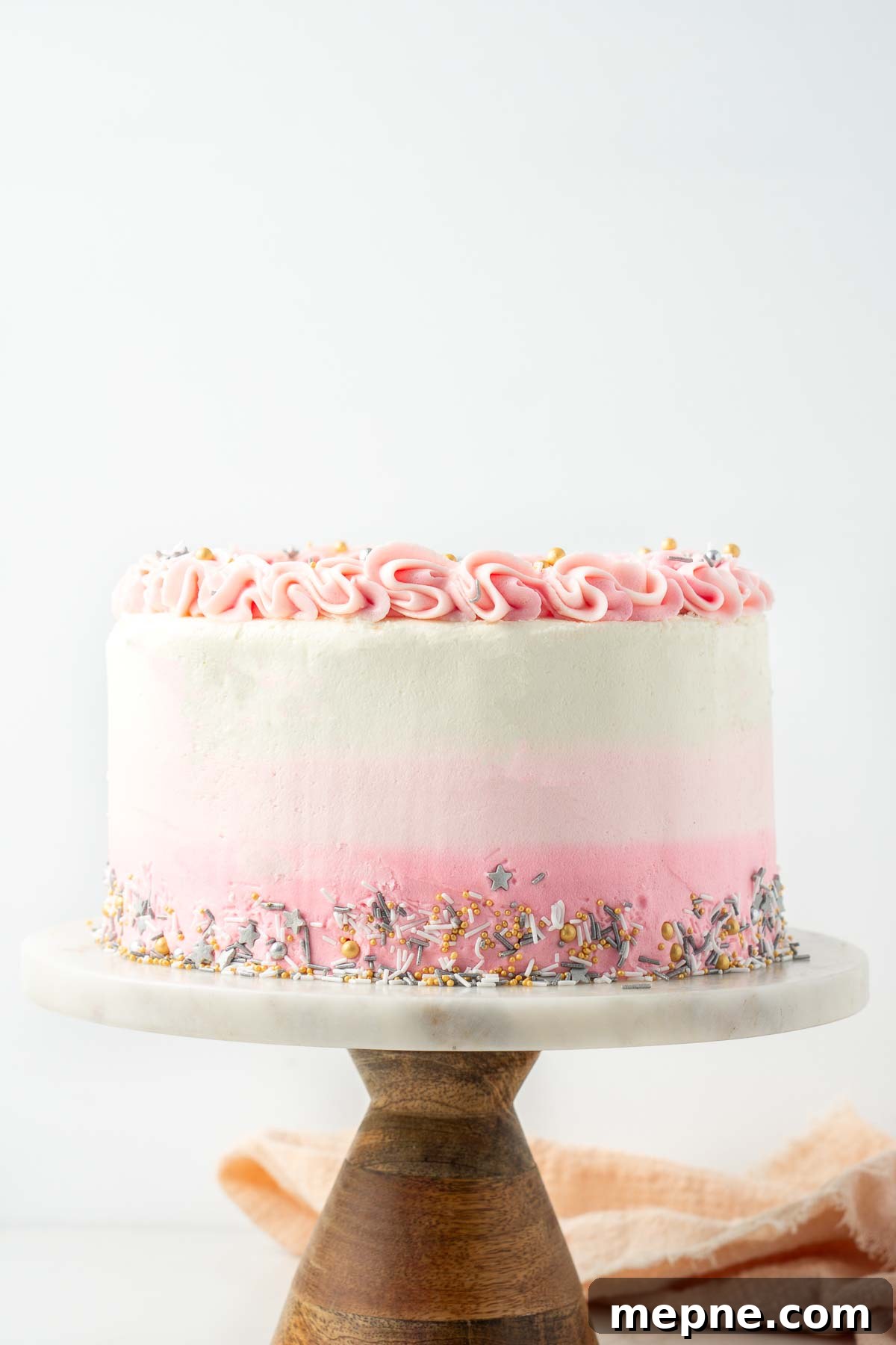 Vegan Vanilla Cake with Fluffy Frosting 10 Vegan vanilla cake with pink ombre frosting on a marble and wood cake stand.