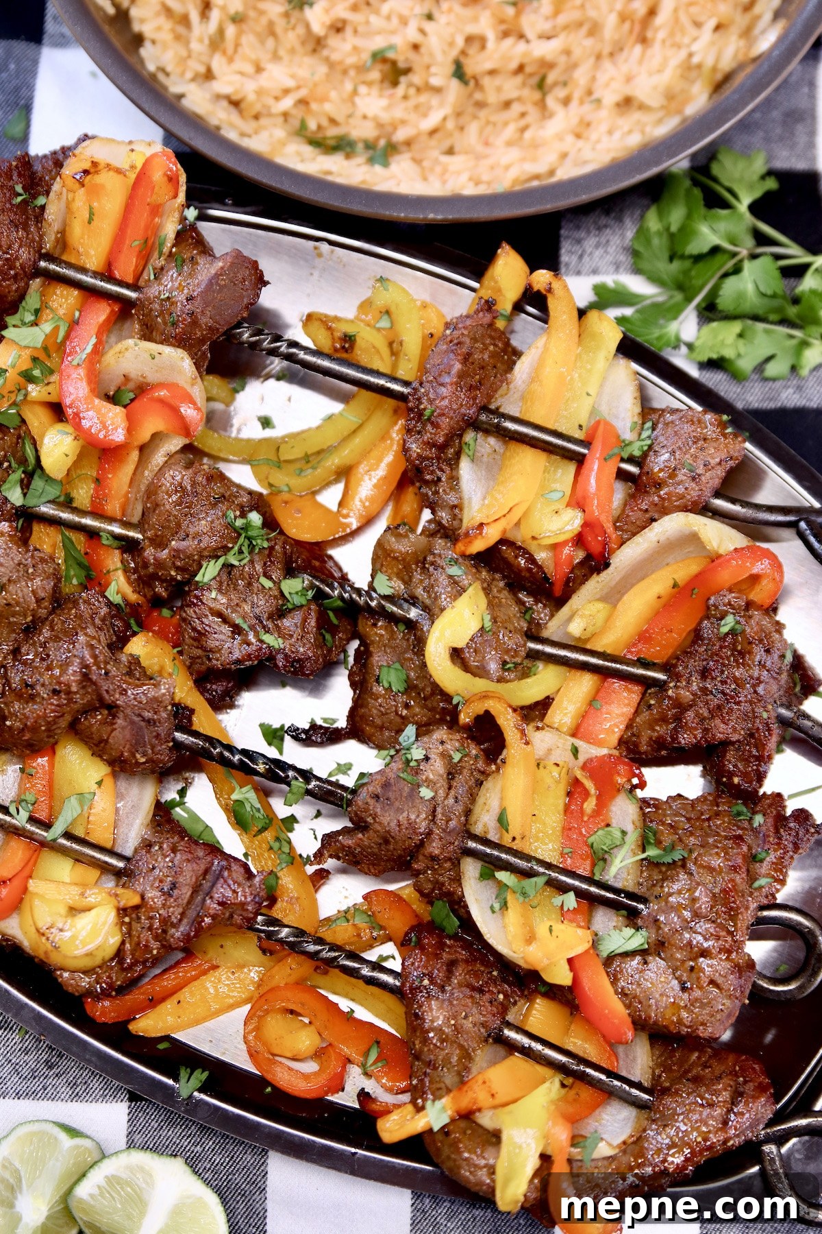 platter of steak and pepper kabobs, bowl of rice.