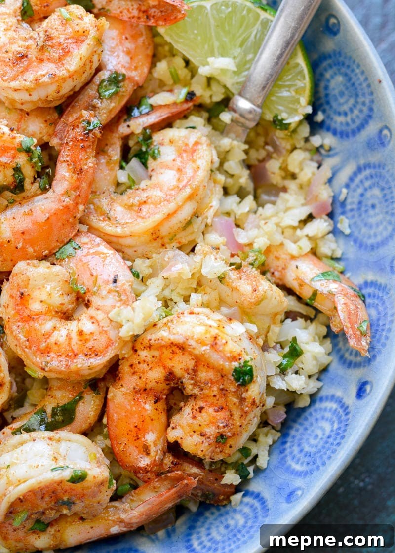Keto Cilantro Lime Shrimp with Cauliflower Rice 2 a blue bowl filled with fluffy cilantro lime cauliflower rice topped with juicy, buttery shrimp