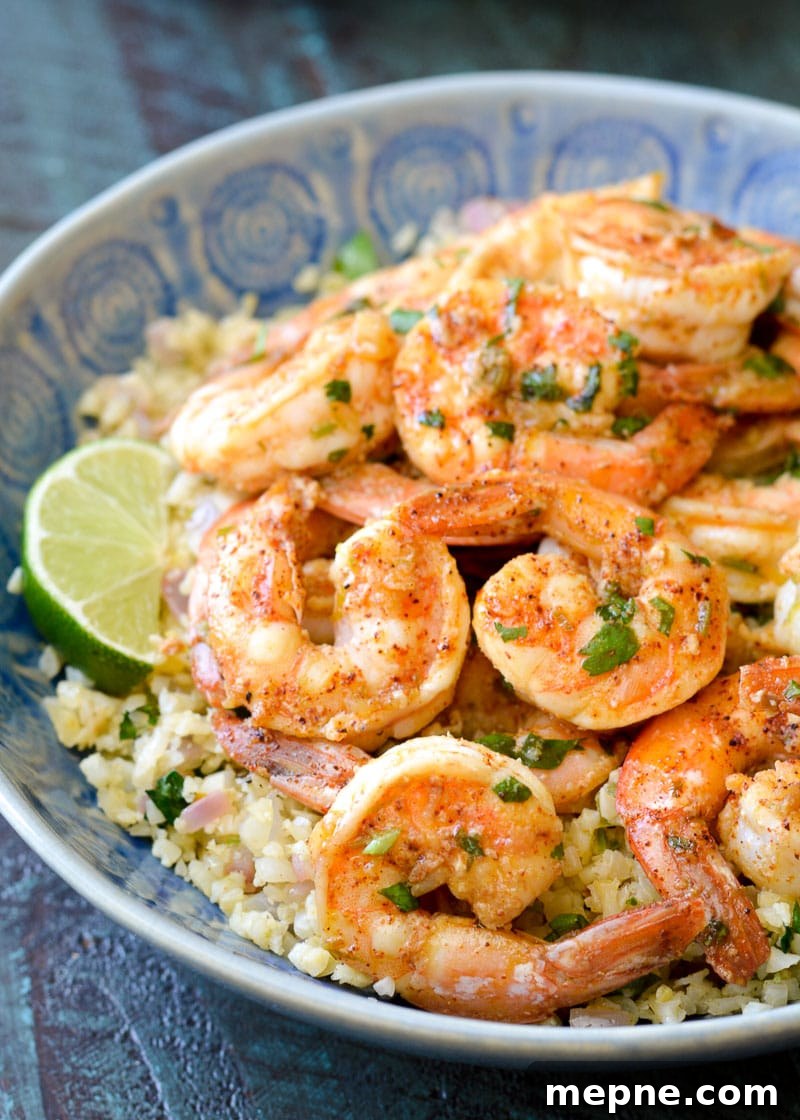Keto Cilantro Lime Shrimp with Cauliflower Rice 3 Easy cilantro lime shrimp and cauliflower rice garnished with lime wedges in a bowl