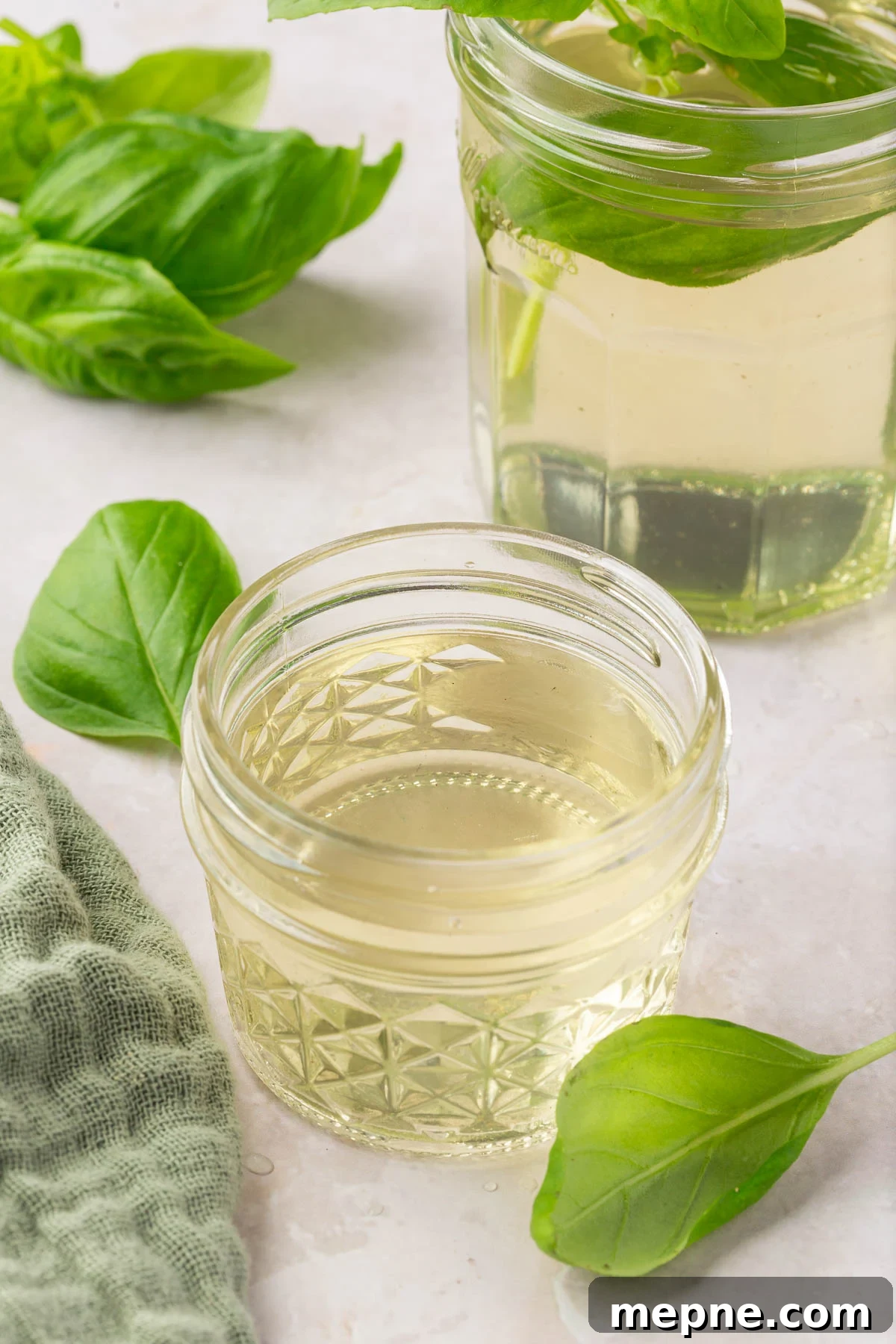 Fresh Basil Lemonade Recipe 12 Two jars of basil simple syrup with fresh basil leaves surrounding them.