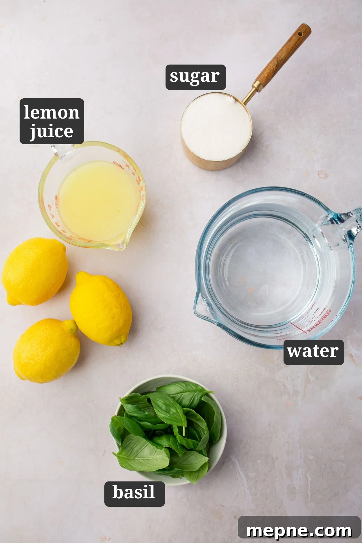 Fresh Basil Lemonade Recipe 3 An overhead view of ingredients to make basil lemonade on a table including granulated sugar, fresh lemon juice, water, and fresh basil leaves with text overlays over each ingredient saying what it is.