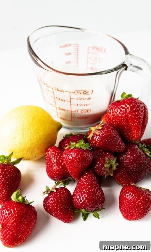 Homemade Strawberry Syrup for Cocktails and Mocktails 3 strawberries, lemon and sugar sitting on white table