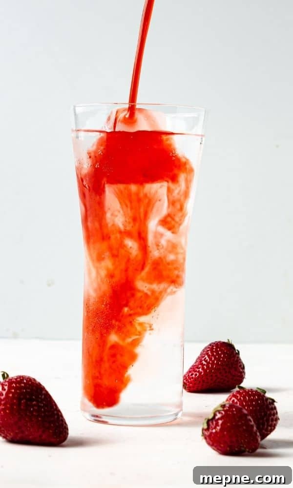 Homemade Strawberry Syrup for Cocktails and Mocktails 5 strawberry syrup pouring into water