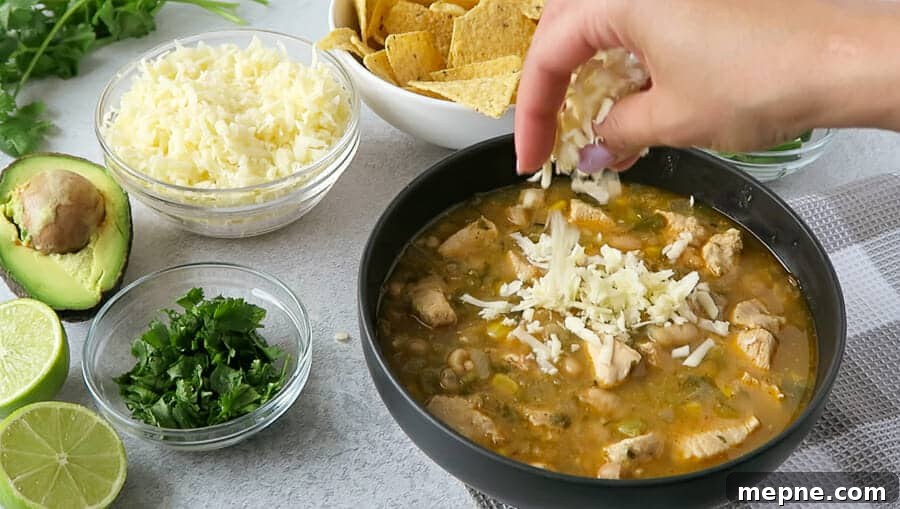 Instant Pot White Chicken Chili: Dairy Free Recipe 7 monterey jack cheese being sprinkled on a bowl of Instant Pot White Chicken Chili (Dairy-free)