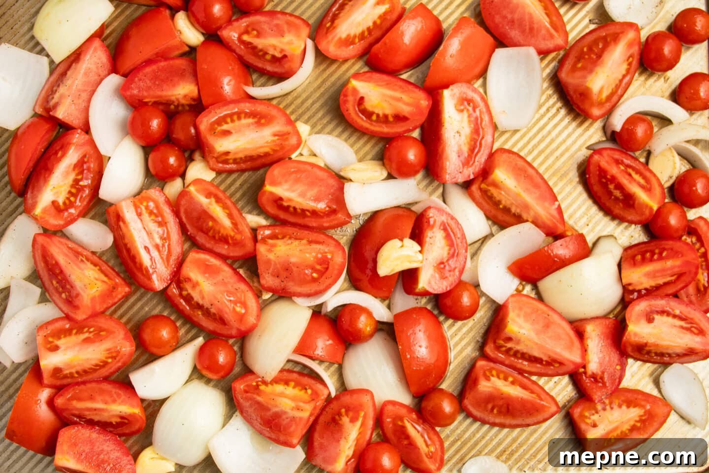 Creamy Roasted Garlic Tomato Soup Recipe 4 This is a picture of tomatoes, onions and garlic on a baking sheet.