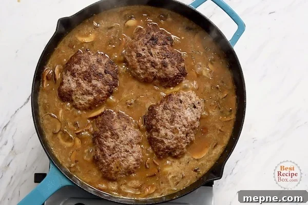 Cooked patties added to mushroom gravy in the skillet