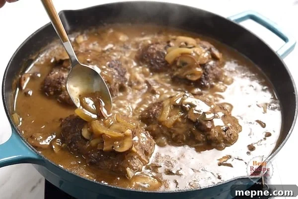 Pouring gravy over the top of the beef patties