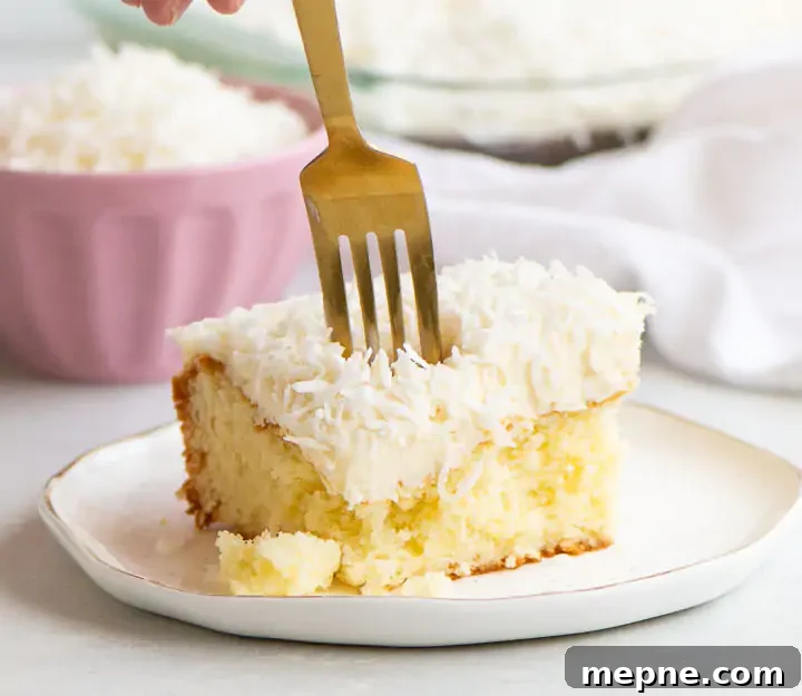 Moist Coconut Sour Cream Cake Recipe with Toasted Coconut 2 fork digging into a slice of coconut sour cream cake on a plate