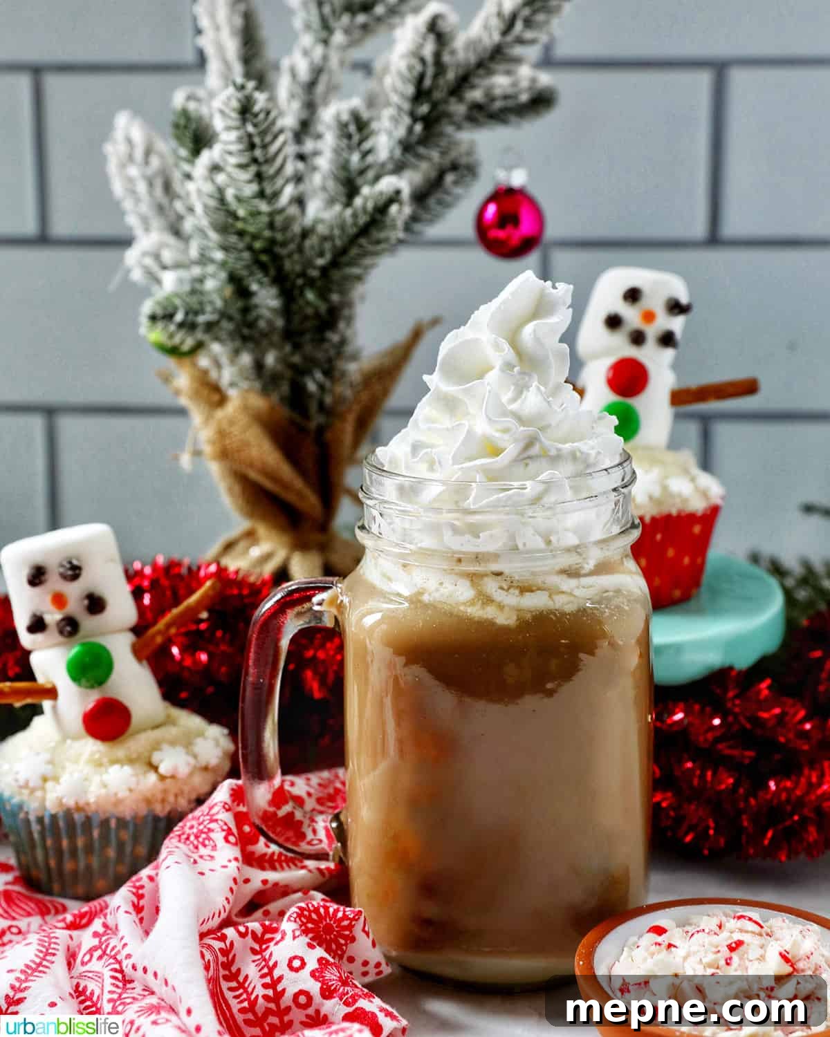 White Chocolate Peppermint Mocha Recipe 14 glass mug of white chocolate peppermint mocha with whipped cream with Christmas holiday decorations in the background.