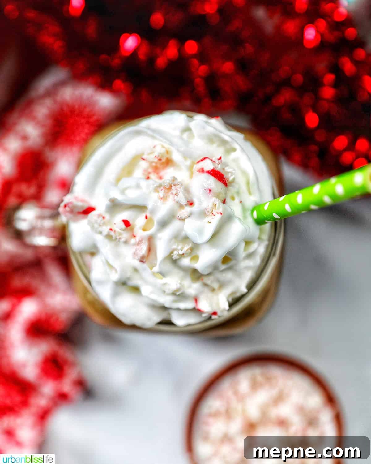 White Chocolate Peppermint Mocha Recipe 3 glass mug of white chocolate peppermint mocha with whipped cream with Christmas holiday decorations in the background.