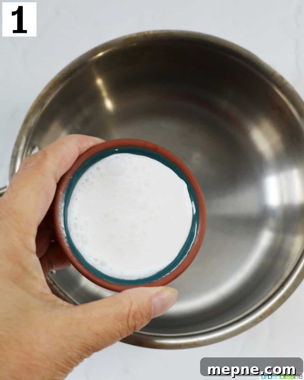 White Chocolate Peppermint Mocha Recipe 5 hand holding cream over a saucepan.