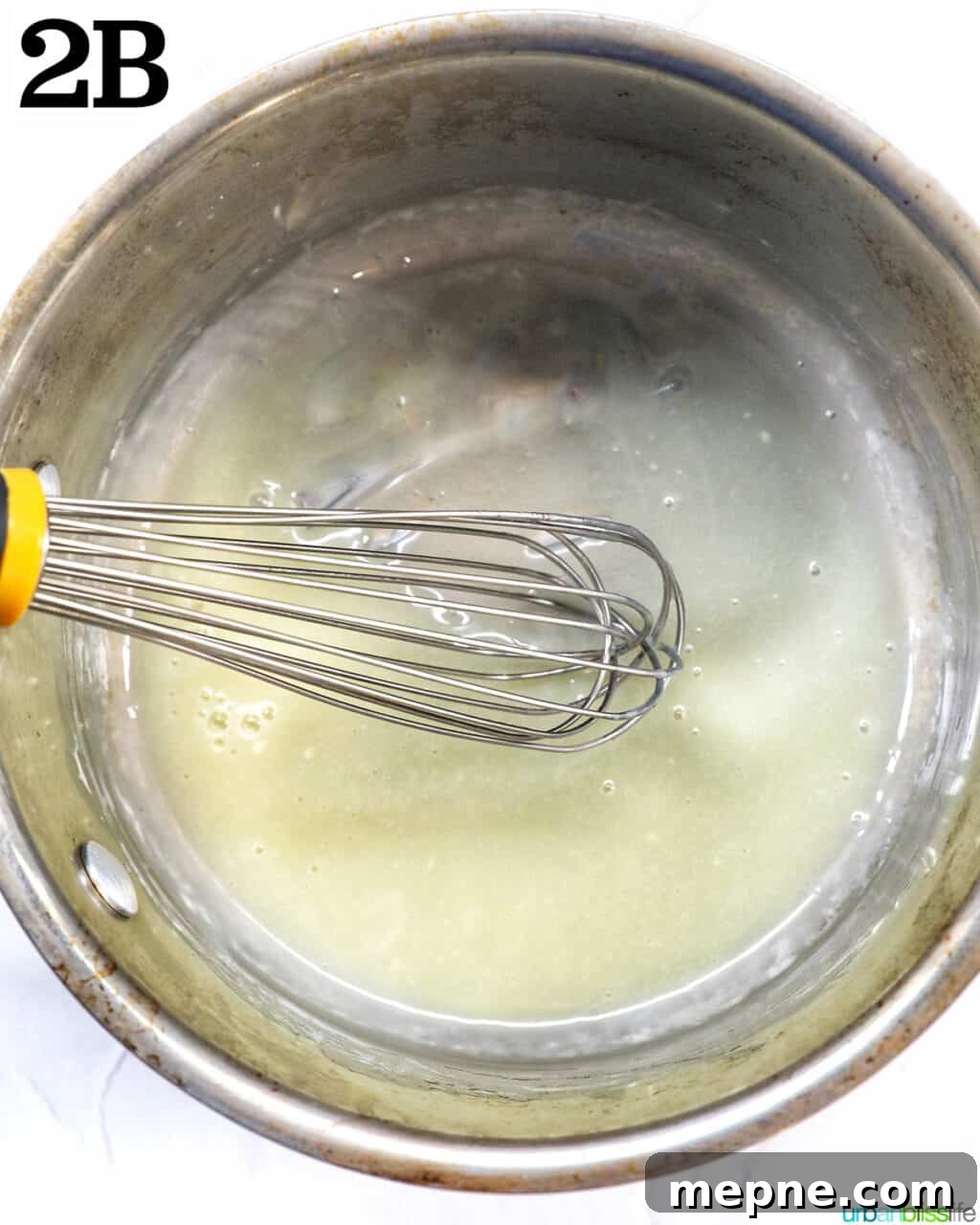 White Chocolate Peppermint Mocha Recipe 7 whisk mixing melted white chocolate and cream in a saucepan.