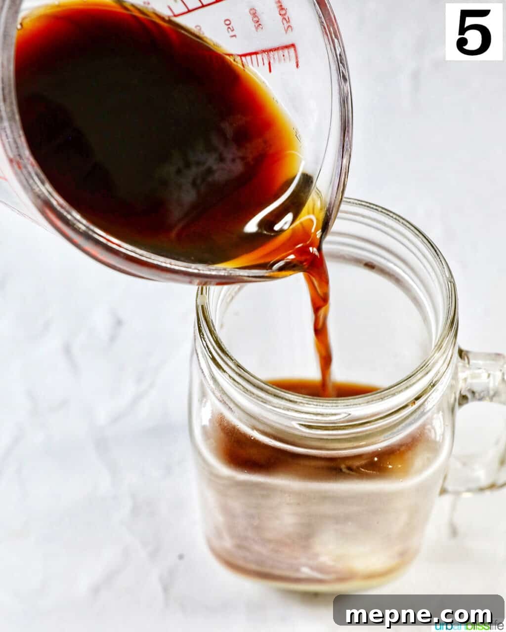 White Chocolate Peppermint Mocha Recipe 10 pouring brewed coffee into a clear glass mug.