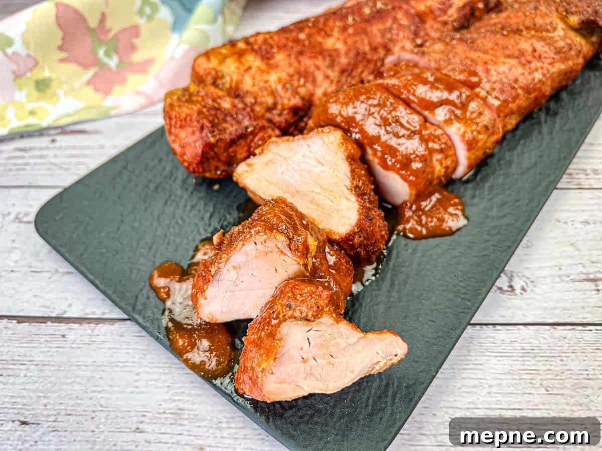 33 BBQ Recipes That Turn Budget Cuts Into Gourmet Meals 12 A plate of Ninja Woodfire Outdoor Grill-Smoked Pork Tenderloin with Mezcal BBQ Sauce.