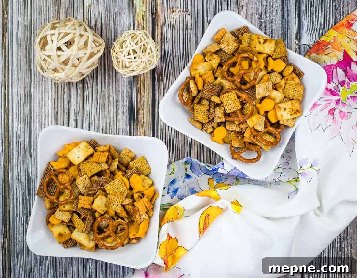 33 BBQ Recipes That Turn Budget Cuts Into Gourmet Meals 30 Two bowls of snack mix with pretzels and cereal on a wooden table, accompanied by decorative balls and a colorful napkin.