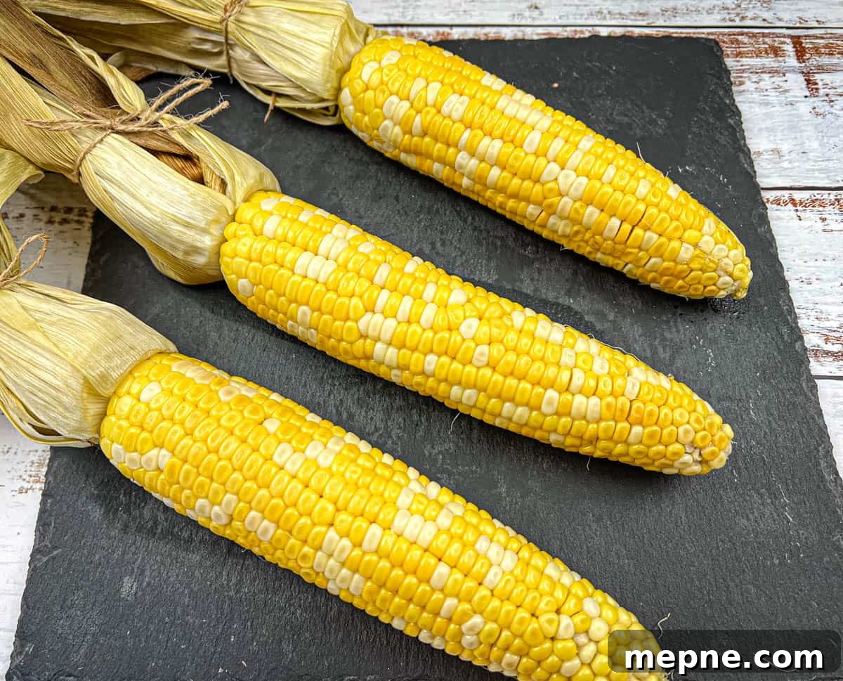 33 BBQ Recipes That Turn Budget Cuts Into Gourmet Meals 6 Three ears of husked corn were arranged on a dark slate plate.