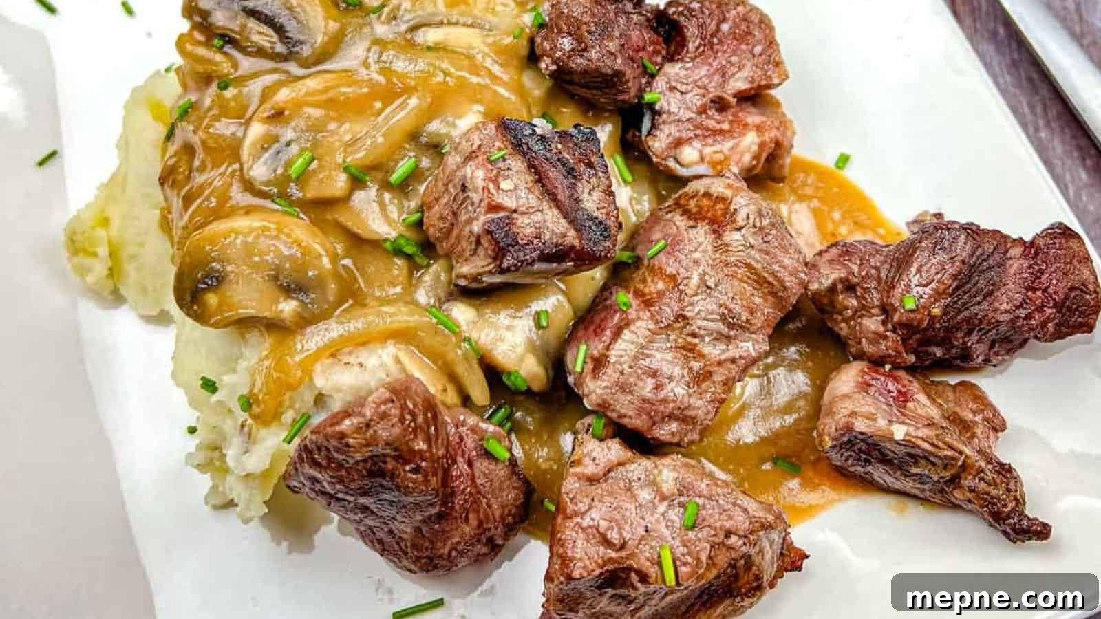 33 BBQ Recipes That Turn Budget Cuts Into Gourmet Meals 10 Texas Roadhouse Beef Tips with mushroom gravy over mashed potatoes, garnished with chives on a white plate.